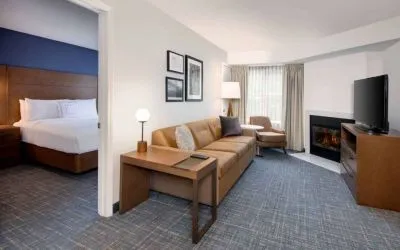 Guest room living area in Sonesta ES Suites Atlanta Alpharetta North Point Mall, with sofa, fireplace,  and TV.