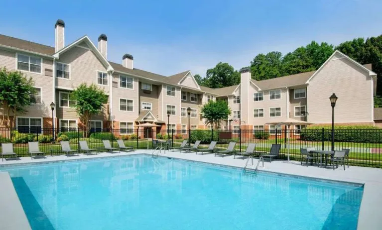 Sonesta ES Suites Atlanta Alpharetta North Point Mall’s outdoor pool has tables and chairs, and sun loungers, by the side.