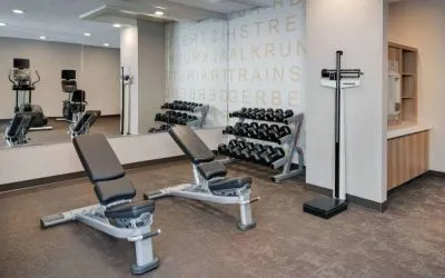 Hotel fitness center equipped with free weights, benches, and various exercise machines.