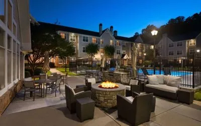 Patio area with fire pit, barbecue, tables and chairs, and armchairs, at Sonesta ES Suites Atlanta Alpharetta North Point Mall.