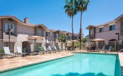 Outdoor pool at Sonesta ES Suites Tempe, featuring shaded tables and chairs, plus sun loungers, by the side.