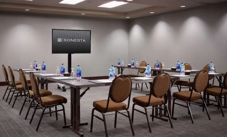 Hotel meeting room, with large table, seating for around 10 attendees, and a large widescreen television.