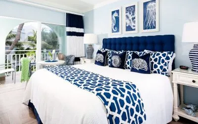 Bright dayroom with white and blue queen size bed and patio view at Oyster Bay Beach Resort. 