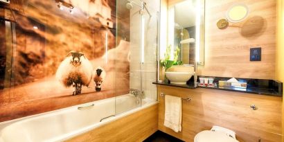 Guest bathroom with shower and tub at Leonardo Royal Hotel Edinburgh Haymarket. 