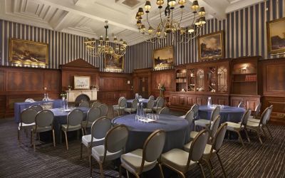 Elegant meeting room featuring round tables, chandeliers, and classic wood paneling at The Grand Brighton.