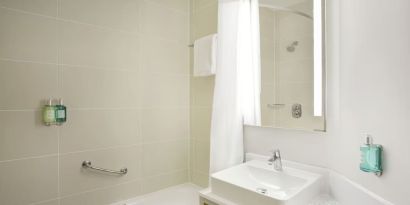 Guest bathroom with shower and tub at Leonardo Hotel Manchester Central.