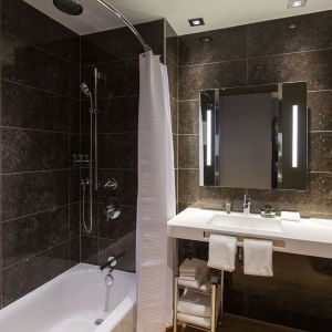 Guest bathroom with shower and tub at AC Hotel Cincinnati At Liberty Center.