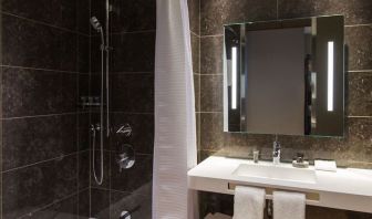 Guest bathroom with shower and tub at AC Hotel Cincinnati At Liberty Center.