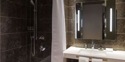 Guest bathroom with shower and tub at AC Hotel Cincinnati At Liberty Center.