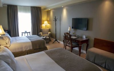 Twin day use room with TV, work desk and lounge seating at Hotel Brossard.