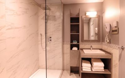 Guest bathroom with shower and free toiletries at Le Chabrol Hotel Et Suites.