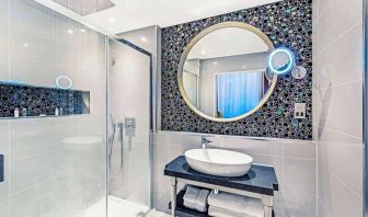Guest bathroom with shower and free toiletries at Mercure Hotel London Hyde Park.