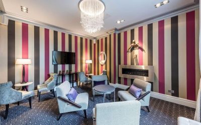 Lounge area with comfortable seating, TV screen and fireplace at Mercure Hotel London Hyde Park.