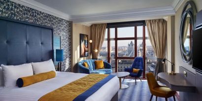Day use room with work desk, lounge area and floor to ceiling window at Leonardo Royal Hotel London City.