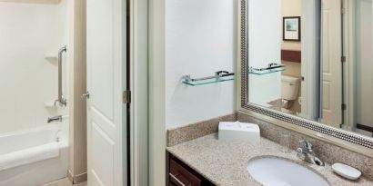 Guest bathroom with shower and tub at Residence Inn By Marriott Hattiesburg.
