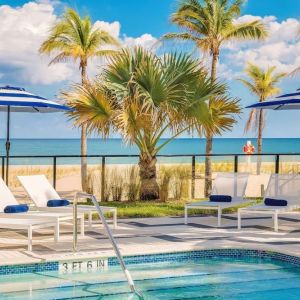 Refreshing outdoor pool surrounded by sun loungers with a view of the ocean at Plunge Beach Resort.

