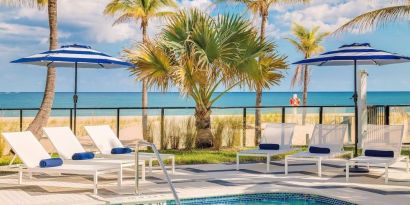 Refreshing outdoor pool surrounded by sun loungers with a view of the ocean at Plunge Beach Resort.
