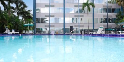 Relaxing outdoor pool with lounge area at EnVision Hotel Miami International Airport.