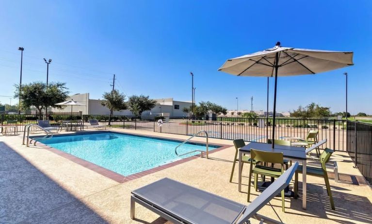 Relaxing outdoor pool with lounge chairs at Spark By Hilton Pearland.