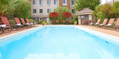 Outdoor pool with lounge chairs at Sonesta ES Suites Dallas Las Colinas.