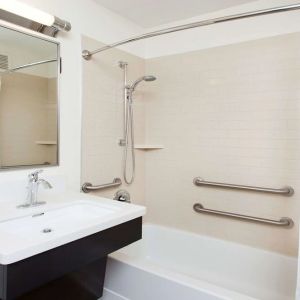 Private guest bathroom with combined shower and tub at Sonesta Simply Suites Dallas Las Colinas.