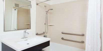 Private guest bathroom with combined shower and tub at Sonesta Simply Suites Dallas Las Colinas.