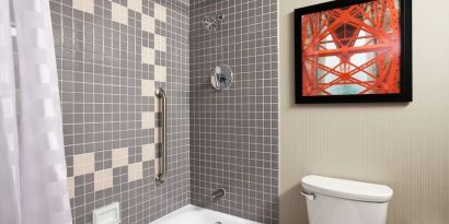 Guest bathroom with shower and tub at Embassy Suites By Hilton San Francisco Airport Waterfront.
