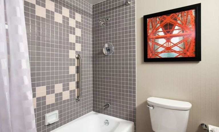 Guest bathroom with shower and tub at Embassy Suites By Hilton San Francisco Airport Waterfront.