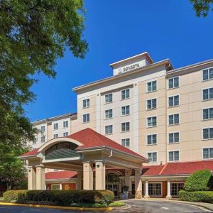Sonesta Atlanta Airport South’s exterior features a covered entrance, well-kept greenery, and stylish red roof tiles.