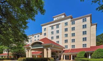 Sonesta Atlanta Airport South’s exterior features a covered entrance, well-kept greenery, and stylish red roof tiles.