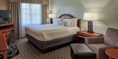 King bed with work desk and lounge seating at Sonesta Atlanta Airport South.