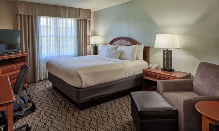 King bed with work desk and lounge seating at Sonesta Atlanta Airport South.