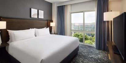 Comfortable king size bed with natural light at Hilton Charlotte Airport.
