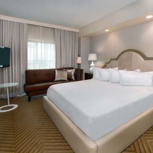 Comfortable king size bed with living area at Hilton Charlotte Airport.
