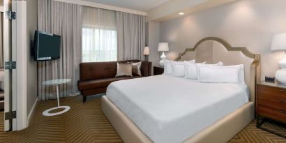 Comfortable king size bed with living area at Hilton Charlotte Airport.
