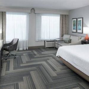 Spacious king bed room with work desk and sofa at Hampton Inn & Suites By Hilton Atlanta Perimeter Dunwoody.
