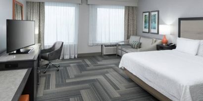 Spacious king bed room with work desk and sofa at Hampton Inn & Suites By Hilton Atlanta Perimeter Dunwoody.
