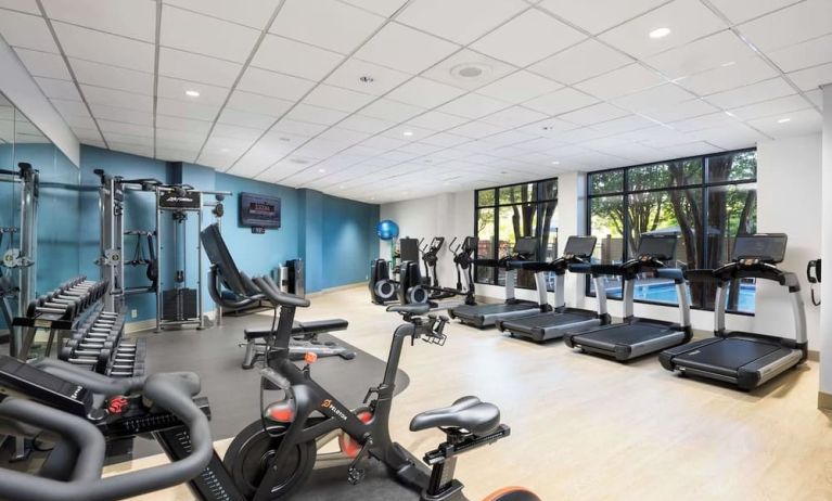 Well-equipped fitness center with a view of the pool at Doubletree By Hilton Houston Medical Center Hotel & Suites.