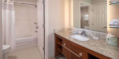 Private guest bathroom with combined shower and tub at Sonesta ES Suites Baltimore BWI Airport.