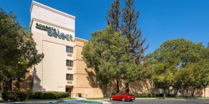 Hotel exterior and parking area at Sonesta Select San Jose Airport.