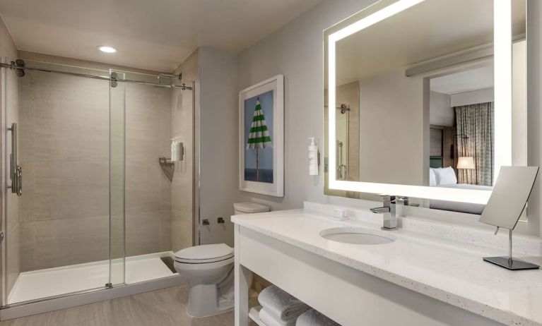 Private guest bathroom with shower and free toiletries at Embassy Suites By Hilton Panama City Beach Resort.