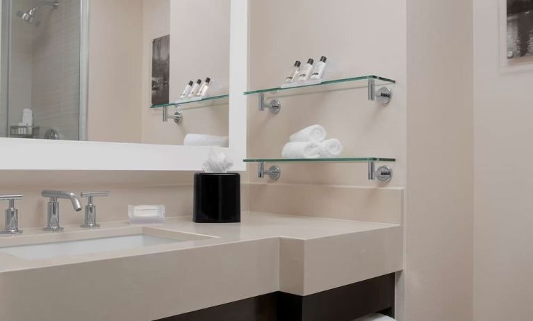 Private guest bathroom with shower and free toiletries at Hilton Garden Inn New York/Times Square Central.