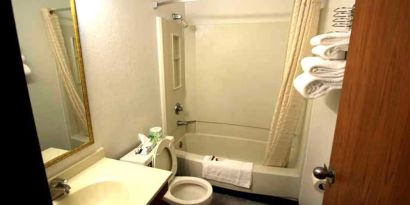 Private guest bathroom with combined shower and tub at Norwood Inn Minneapolis Roseville.