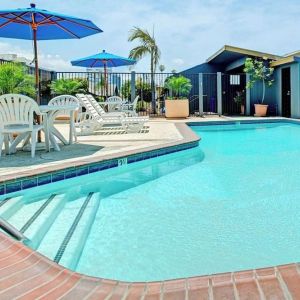 Outdoor pool with lounge chairs at Travelodge LAX By Wyndham.