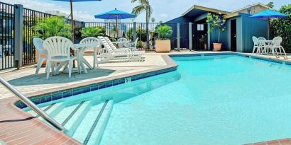 Outdoor pool with lounge chairs at Travelodge LAX By Wyndham.
