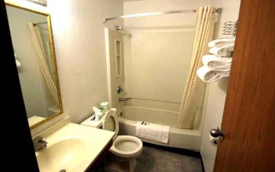 Private guest bathroom with combined tub and shower at Norwood Inn & Suites - Roseville.