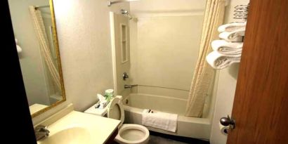 Private guest bathroom with combined tub and shower at Norwood Inn & Suites - Roseville.