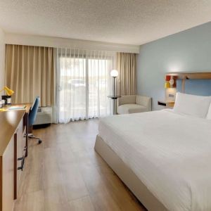 Day use room with king bed, work desk, sofa, TV screen and floor to ceiling window at Sonesta Select Scottsdale At Mayo Clinic Campus.