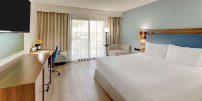 Day use room with king bed, work desk, sofa, TV screen and floor to ceiling window at Sonesta Select Scottsdale At Mayo Clinic Campus.