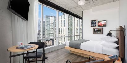Delux king room with work desk and a view of the city at Moxy Boston Downtown.